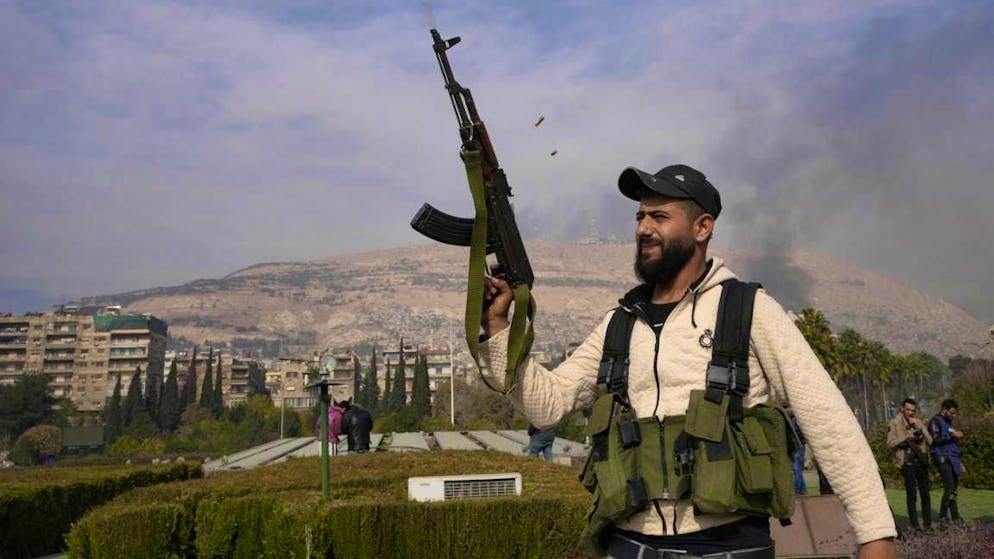 An opposition fighter fires his AK-47 while celebrating the takeover of the city of Damascus in Syria