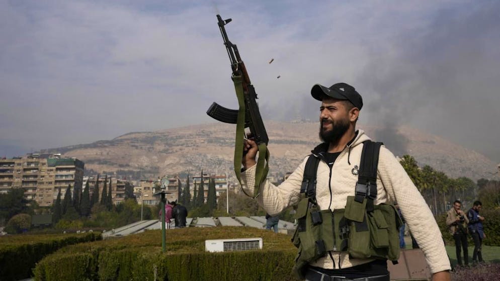 Ein Oppositionskämpfer feuert mit seiner AK-47, während er die Übernahme der Stadt Damaskus in Syrien feiert