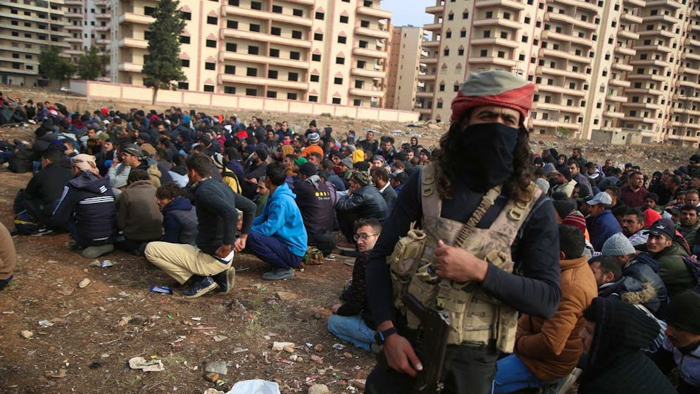 Mitglieder der Sicherheitskräfte der syrischen Regierung werden auf einem Feld in Homs von Rebellen bewacht. (8. Dezember 2024)