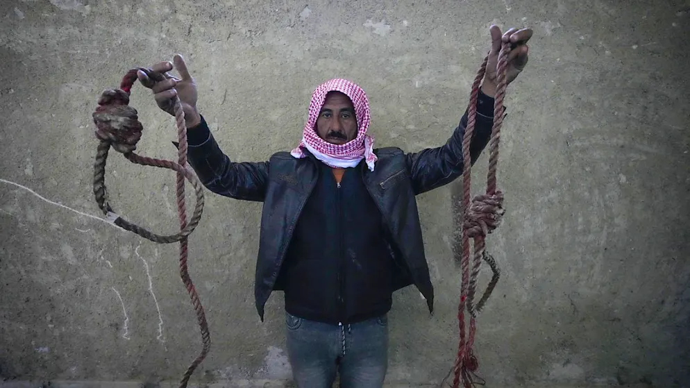Un homme montre deux cordes en forme de nœud coulant, trouvées dans la tristement célèbre prison militaire de Saydnaya. Des foules se rassemblent pour entrer dans la prison, connue sous le nom d'« abattoir humain », certains espérant retrouver des parents qui y ont été détenus.