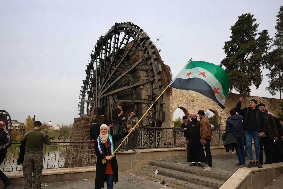 Eine Frau schwenkt die Fahne der syrischen Revolution, nachdem die Rebellen die Kontrolle über die Stadt Hama erlangt haben. (Bild vom 7. Dezember)