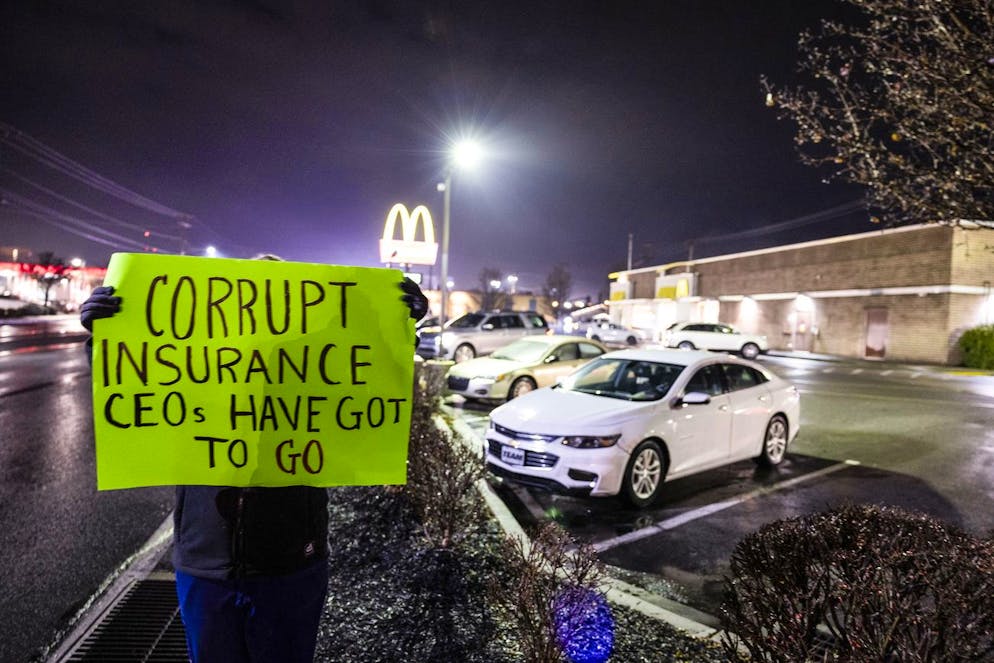 Une femme brandit une pancarte devant le McDonald's où Luigi Mangione a été arrêté.