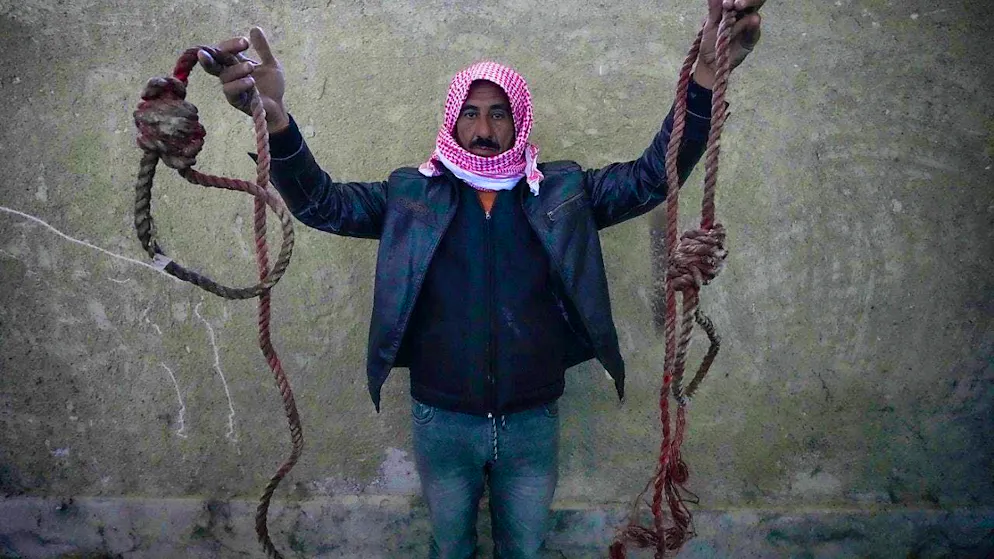 dpatopbilder - A man holds up two ropes in the shape of nooses found in the notorious Saidnaya military prison north of Damascus. Thousands of inmates have been released after the rebels toppled Bashar al-Assad's regime on Sunday. Photo: Hussein Malla/AP/dpa