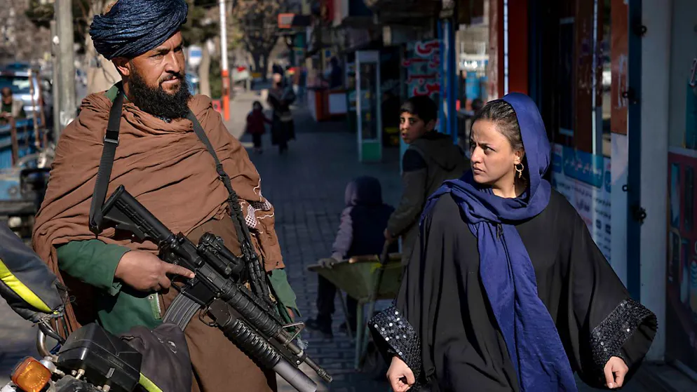 ARCHIV - Ein Taliban-Kämpfer steht Wache während eine Frau vorbeiläuft. Foto: Ebrahim Noroozi/AP/dpa