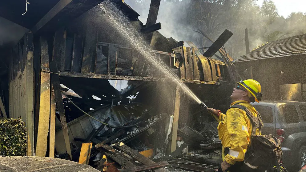 A firefighter hoses down hot spots around a fire-ravaged property after the Franklin Fire swept through Tuesday, Dec. 10, 2024, in Malibu, Calif. (