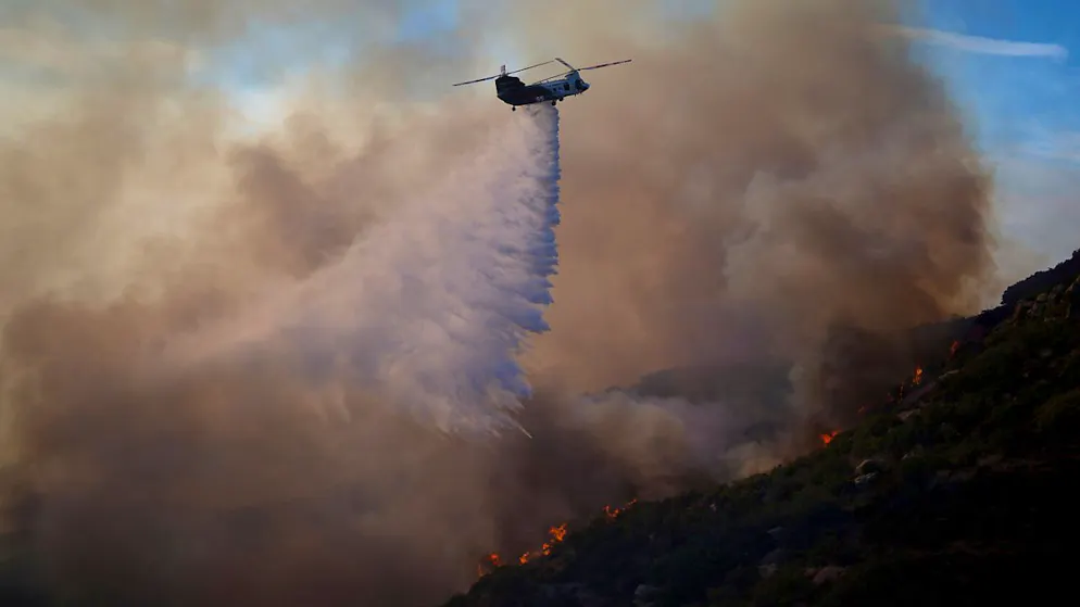 Ein Helikopter wirft Wasser auf das Franklin-Feuer in Malibu, USA. Foto: Eric Thayer/AP/dpa