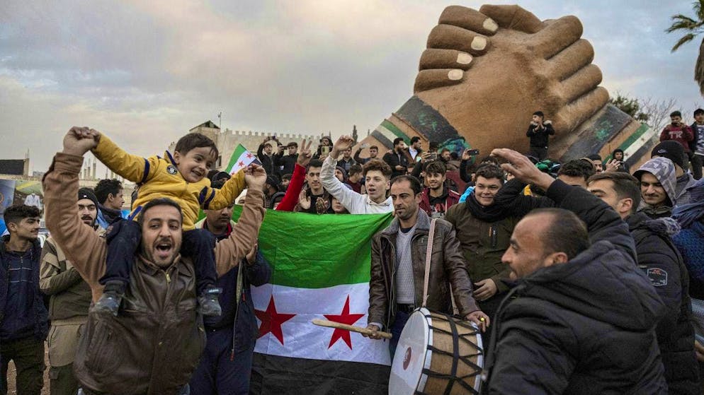 People gather on the streets of the Syrian city of Manbij on December 8 to celebrate the fall of the Assad regime.