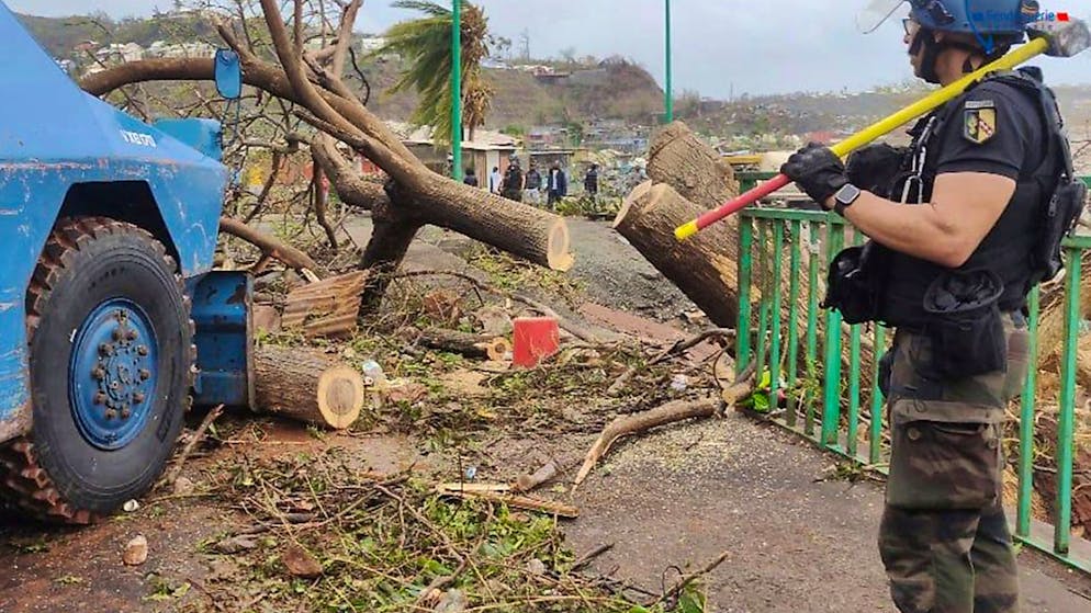 HANDOUT - Ein Mitglied der Gendarmerie Nationale, beobachtet ein gepanzertes Fahrzeug, das am 15. Dezember  in Mayotte eine Straße räumt. Frankreich schickt Rettungsteams und Versorgungsgüter in sein Überseegebiet im Indischen Ozean, das große Zerstörungen durch den Zyklon «Chido» erlitten hat. Foto: Uncredited/Gendarmerie Nationale/AP/dpa - ACHTUNG: Nur zur redaktionellen Verwendung und nur mit vollständiger Nennung des vorstehenden Credits