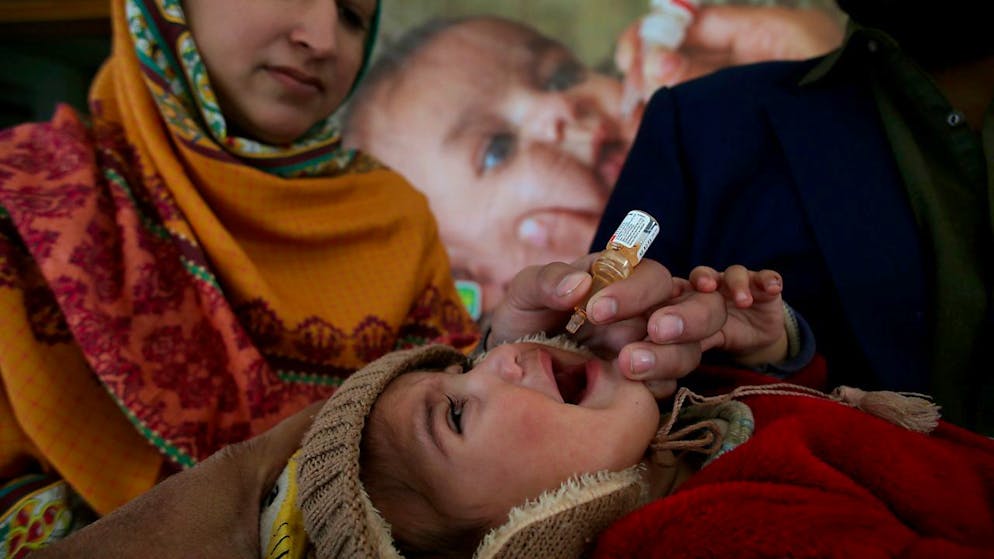 Ein Gesundheitsarbeiter verabreicht einem Kind in einem Gesundheitszentrum einen Polio-Impfstoff. Foto: Muhammad Sajjad/AP/dpa