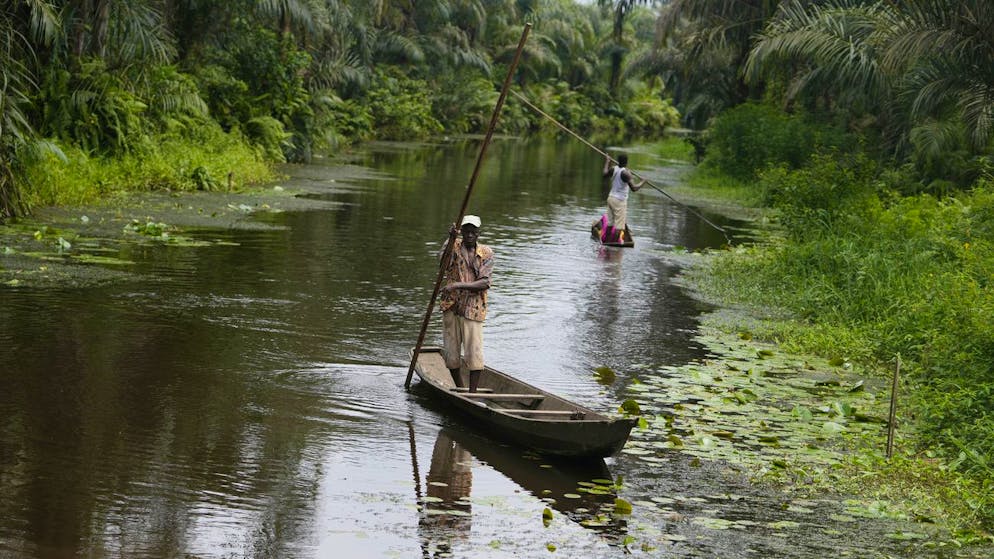 Ein Mann paddelt ein Kanu in der Nähe eines heiligen Voodoo-Waldes in Adjarra, Benin.