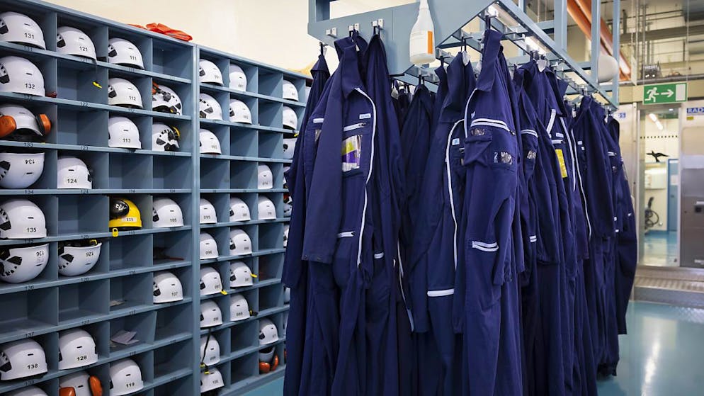 Der Rückbau des Kernkraftwerks Mühleberg geht gut voran - Gallery. Schutzhelme und Schutzanzüge für die Mitarbeitenden in einer Garderobe.