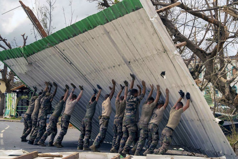 Des soldats soulevant une barrière effondrée à Mayotte. 
