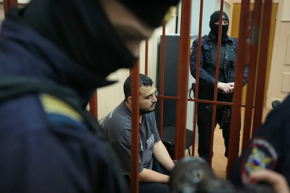 L'homme, que les agences de presse Tass et RIA-Novosti ont identifié comme Akhmadzhon Kurbonov, soupçonné d'être impliqué dans le meurtre du lieutenant-général Igor Kirillov, est assis dans une cage dans une salle d'audience du tribunal du district de Basmanny à Moscou, en Russie, le jeudi 19 décembre 2024.