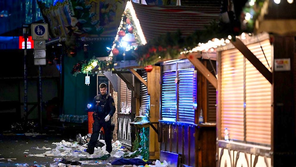 A police officer examines the crime scene at the Christmas market. Photo: Heiko Rebsch/dpa