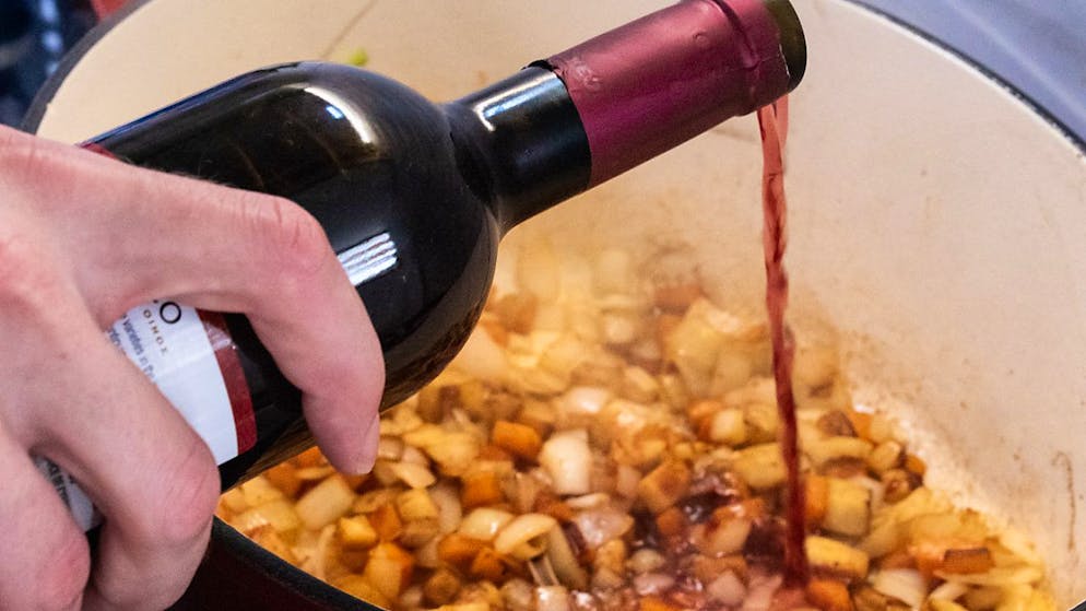 ILLUSTRATION - Ein Koch gießt Rotwein in eine Soße (Symbolbild). Foto: Katharina Frenzel/dpa-tmn/dpa