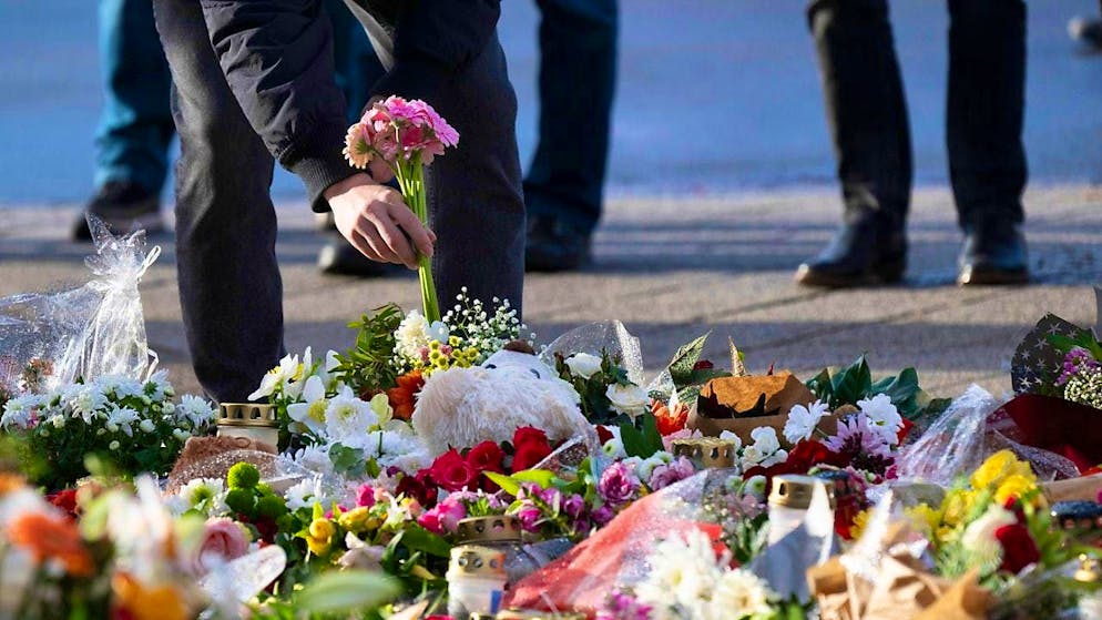 A passer-by lays flowers in front of the entrance to St. John's Church.