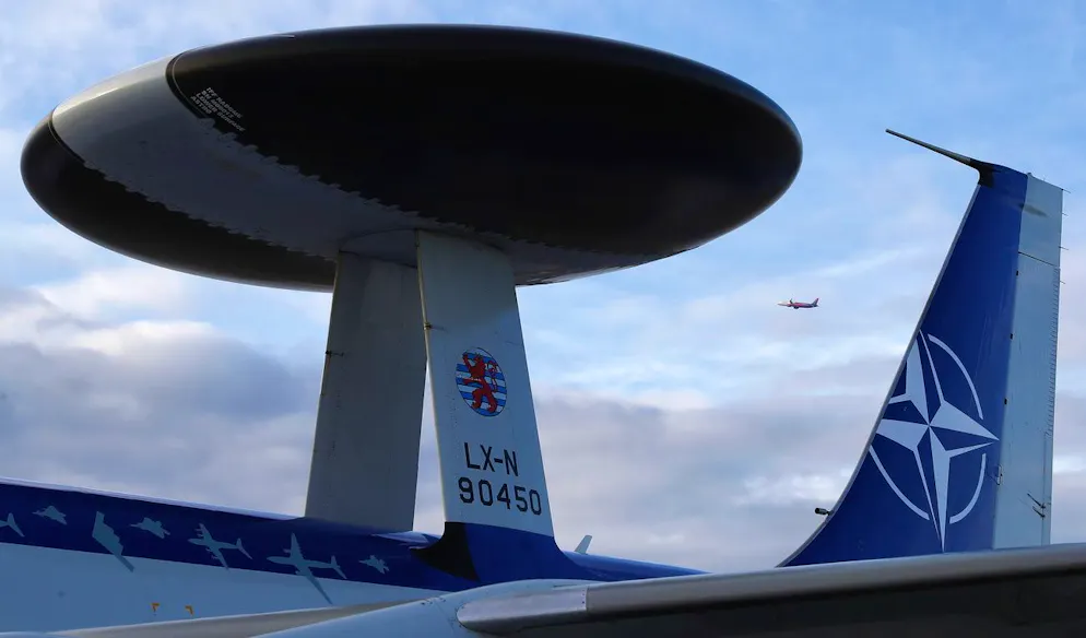 Un avion de ligne civil passe devant l'antenne radar de l'avion militaire du système aéroporté de détection et de contrôle (AWACS) de l'OTAN qui vient d'atterrir à l'aéroport militaire d'Otopeni (base aérienne n° 90), près de Bucarest, en Roumanie, le 17 janvier 2023. L'AWACS est utilisé par l'OTAN avec les avions adaptés pour la surveillance radar à longue portée.