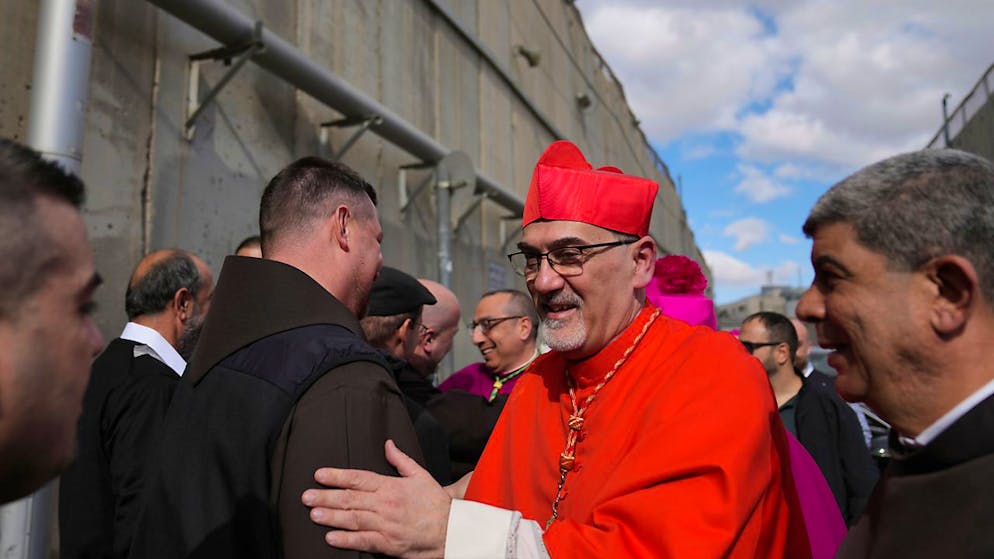 Erzbischof Pierbattista Pizzaballa, der oberste römisch-katholische Geistliche im Heiligen Land, wird von der örtlichen Gemeinde empfangen, während er einen israelischen Militärkontrollpunkt von Jerusalem aus durchquert. Foto: Nasser Nasser/AP/dpa