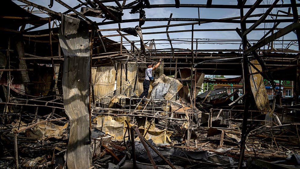 ARCHIV - Ein Mann sammelt Kupferdrähte auf einem Markt, der durch russischen Beschuss zerstört wurde. Foto: Evgeniy Maloletka/AP/dpa