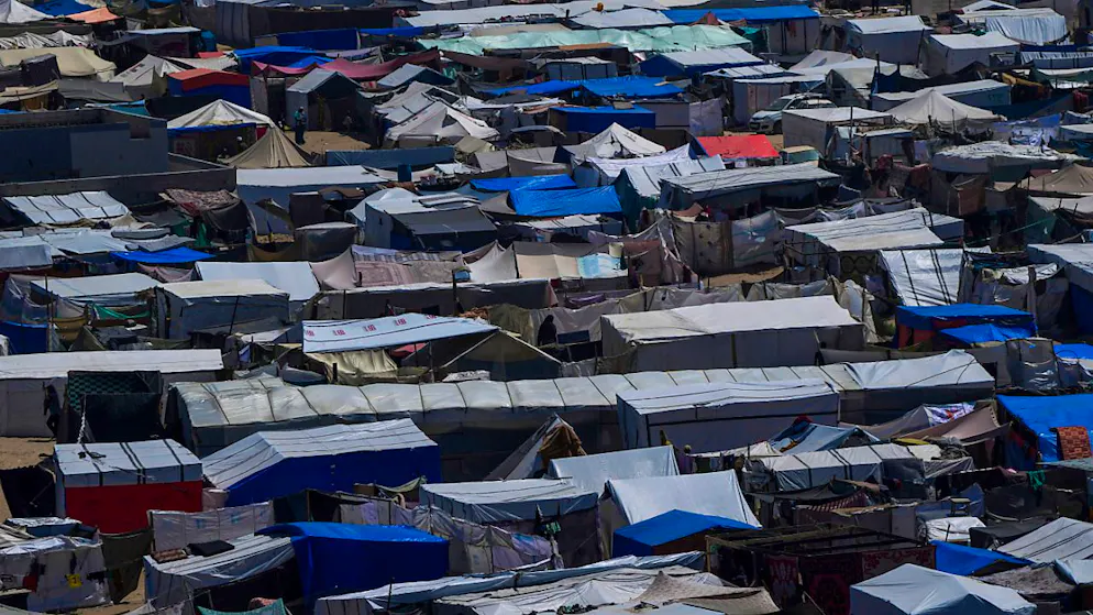 ARCHIV - Palästinenser, die durch die israelische Luft- und Bodenoffensive im Gazastreifen vertrieben wurden, gehen durch ein behelfsmäßiges Zeltlager. Foto: Abdel Kareem Hana/AP/dpa
