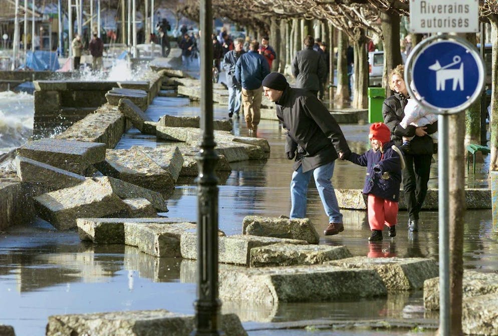 Des curieux observent les dalles du quai de Lutry souflées par la tempête qui a fait rage sur les bords du Lac Léman, le 26 décembre 1999.