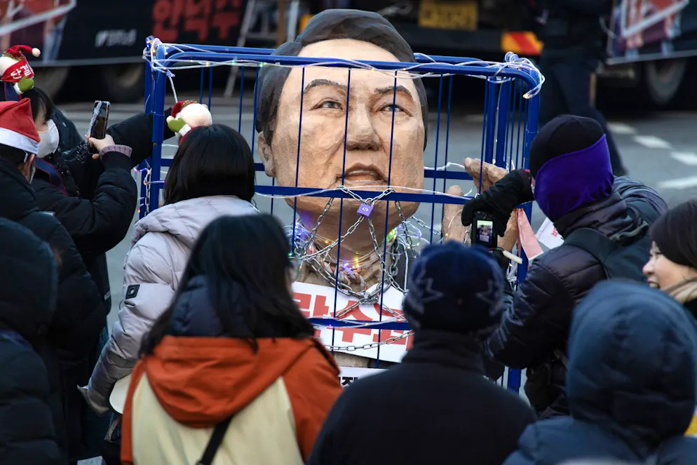 Des manifestants brandissent une effigie enchaînée du président sud-coréen Yoon Suk Yeol lors d'un rassemblement à Séoul, le 21 décembre 2024, organisé par des groupes civiques exigeant sa démission.