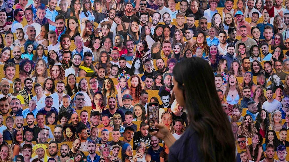 ARCHIVE - A woman photographs a wall with portraits of the victims at the site of the Nova music festival, where hundreds of revelers were killed and abducted by the Islamist Hamas and taken to the Gaza Strip. The first anniversary of the Islamist Hamas attack. Photo: Ariel Schalit/AP/dpa