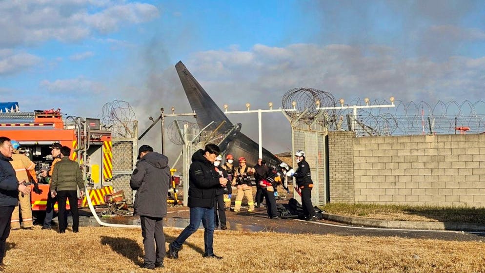 Feuerwehrleute und Mitglieder des Rettungsteams arbeiten auf dem internationalen Flughafen von Muan. Bei der Landung am internationalen Flughafen von Muan in Südkorea ist ein Passagierflugzeug verunglückt. Foto: Maeng Dae-hwan/Newsis/AP/dpa