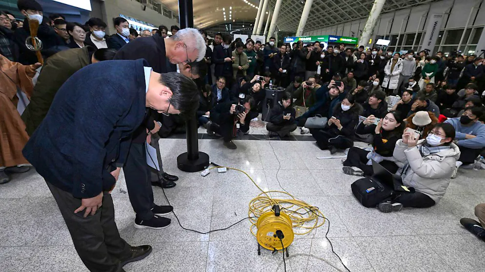 dpatopbilder - Der CEO von Jeju Air, Kim E-bae (l), und andere Mitglieder der Geschäftsführung verbeugen sich auf dem internationalen Flughafen Muan vor den Angehörigen der Passagiere. Foto: Uncredited/YONHAP/AP/dpa