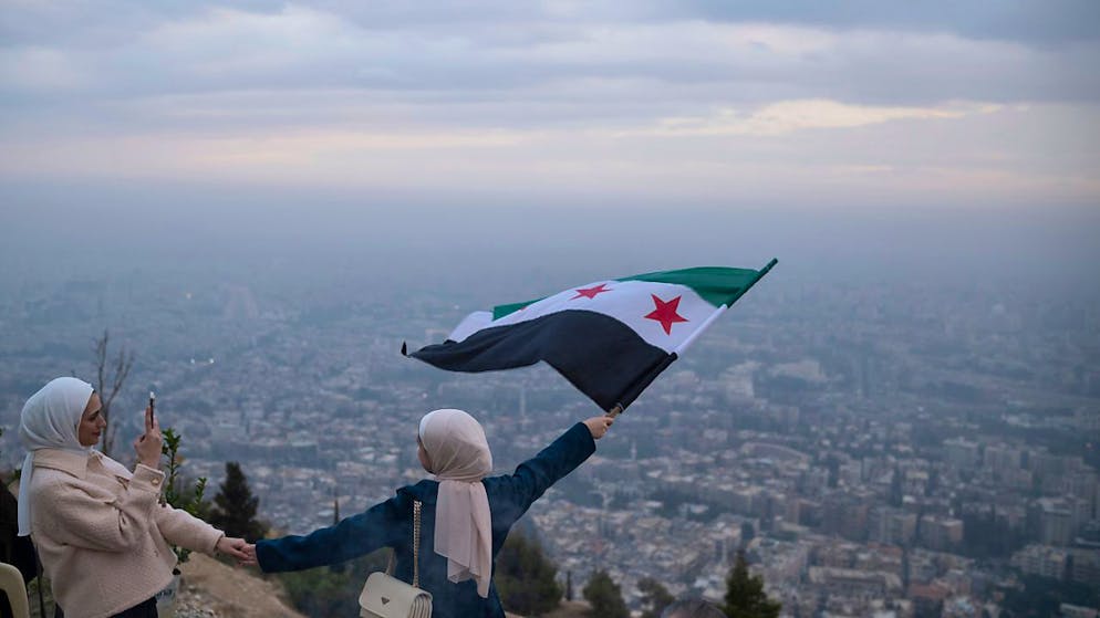 ARCHIVE - A young woman poses for a photo with a flag of the Syrian Opposition on an Aussichtspunkt auf dem Berg Qasiyun above the city of Damascus. Photo: Leo Correa/AP/dpa