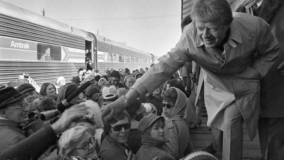 ARCHIVE - US President-elect Jimmy Carter leans forward to shake hands with some passengers on the "Peanut Special" to Washington. Photo: Uncredited/AP/dpa
