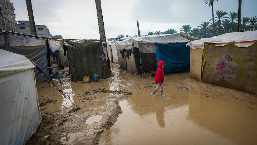 Ein junges Mädchen in einer überschwemmten Straße. Foto: Abdel Kareem Hana/AP/dpa