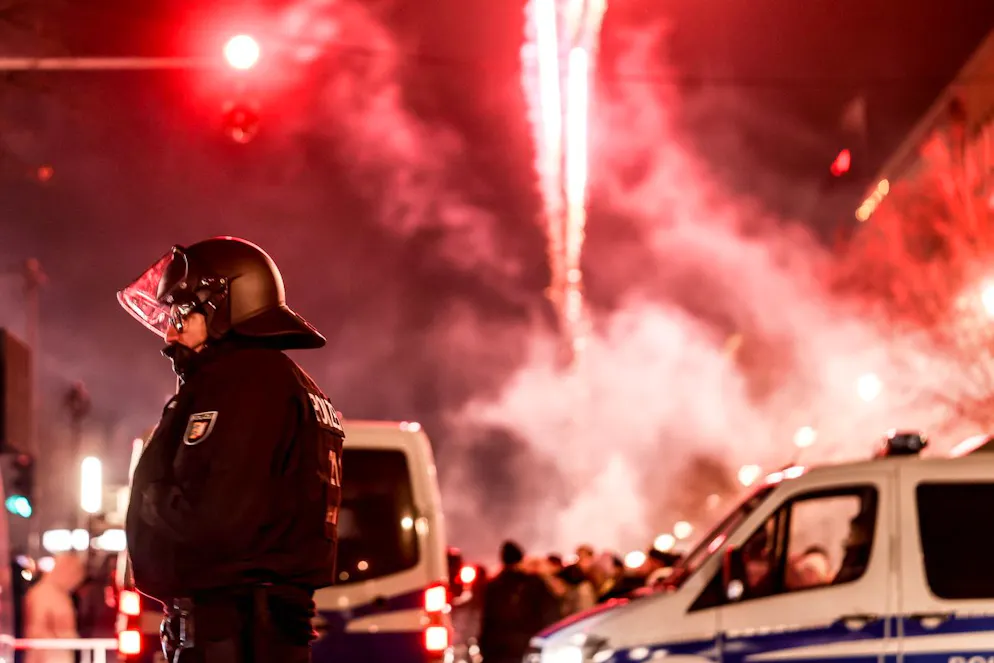 epa11800398 Fireworks illuminate the sky behind a police officer during New Year's Eve celebrations in Berlin, Germany, 31 December 2024. EPA/FILIP SINGER