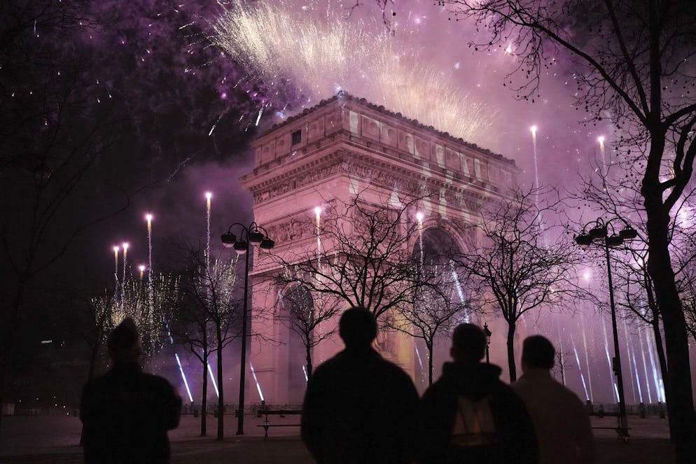 Un spectacle de lumière est projeté sur l'Arc de Triomphe alors que des feux d'artifice explosent pendant les célébrations du Nouvel An sur les Champs Elysées à Paris, France, mercredi 1er janvier 2025. (AP Photo/Thibault Camus)