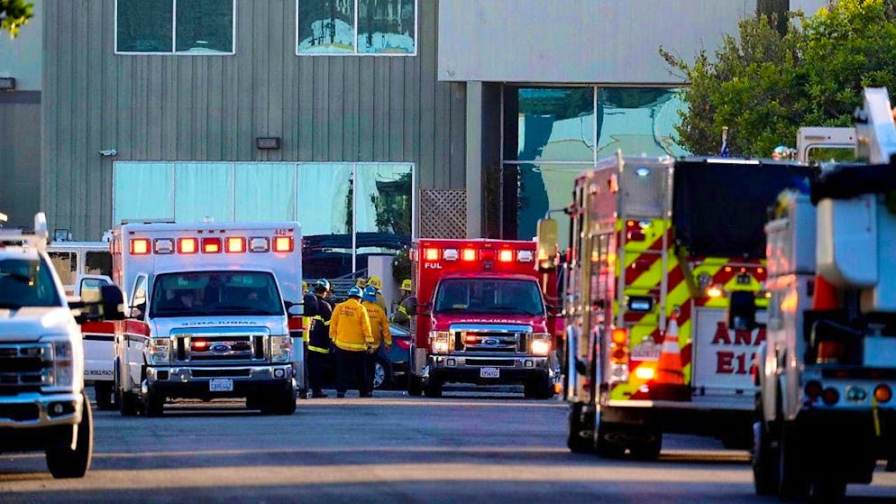 Rescue workers work on a building on which a small plane crashed. Photo: Damian Dovarganes/AP/dpa