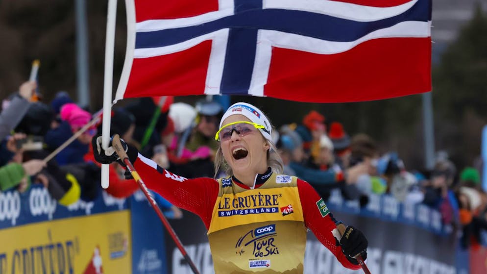 Therese Johaug läuft mit der norwegischen Flagge als Siegerin auf der Alpe Cermis ein
