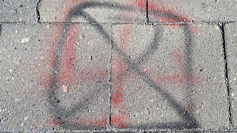 ARCHIV - Auf einem Gehweg am Platz der Jugend ist ein unkenntlich gemachtes Hakenkreuz zu sehen. Foto: Patrick Pleul/dpa