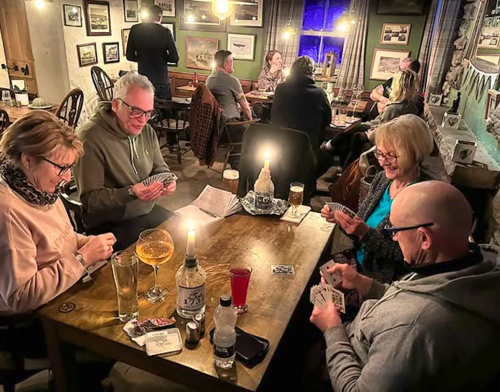 The snowed-in guests pass the time playing cards, among other things.