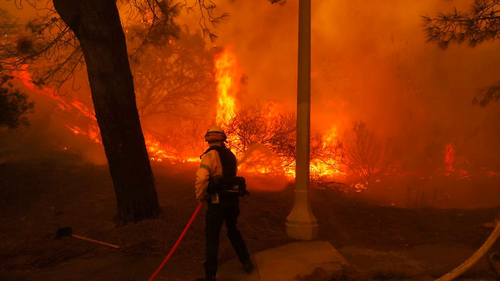 Ein Feuerwehrmann kämpft gegen das sich ausbreitende Palisades-Feuer im Stadtteil Pacific Palisades von Los Angeles. Foto: Etienne Laurent/FR172066 AP/AP/dpa