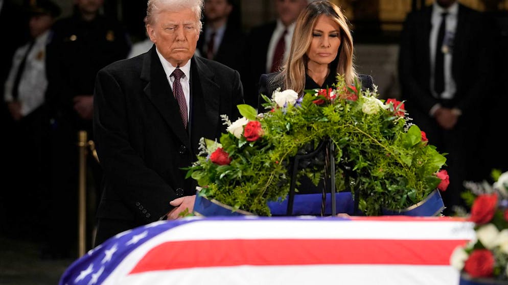 Der designierte US-Präsident Donald Trump und seine Frau Melania Trump stehen vor dem mit einer Flagge drapierten Sarg des verstorbenen ehemaligen Präsidenten Jimmy Carter, der in der Rotunde des US-Kapitols in Washington aufgebahrt ist. Foto: J. Scott Applewhite/AP/dpa