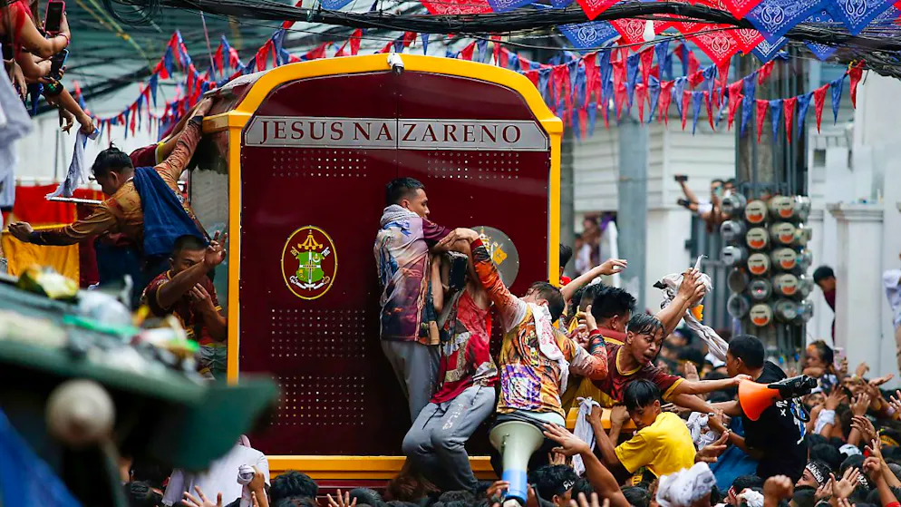 Gläubige versuchen, während der jährlichen Prozession auf einen glasbedeckten Wagen mit dem Bildnis von Jesus Nazareno zu steigen. Foto: Basilio Sepe/AP/dpa