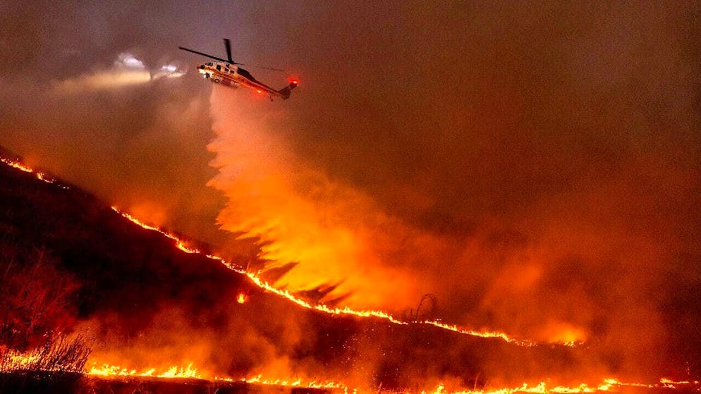 A helicopter drops water on the Kenneth Fire in the West Hills of Los Angeles.