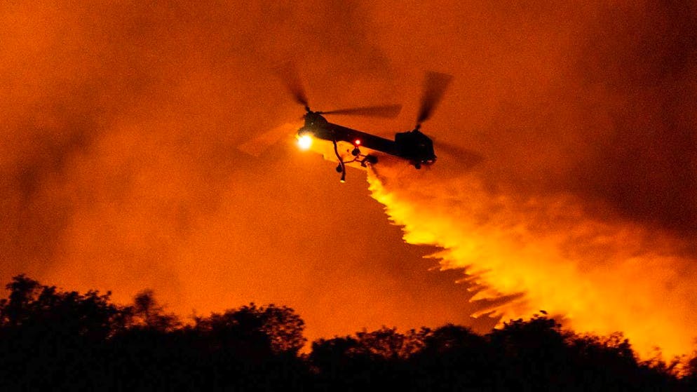 dpatopbilder - A helicopter drops water on the Palisades Fire in Mandeville Canyon. Photo: Etienne Laurent/AP/dpa