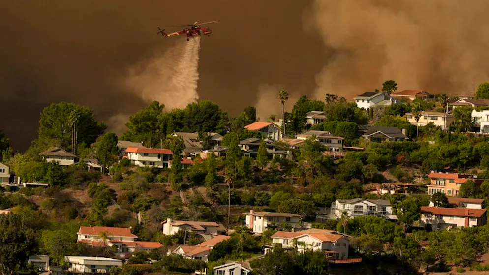 Beim Vorrücken des Palisades-Feuers im Mandeville Canyon in Los Angeles wird Löschwasser aus einem Helikopter auf Häuser geworfen.