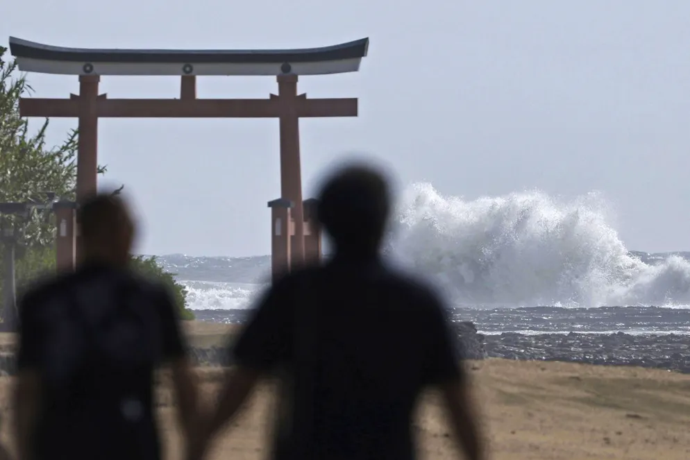 Des personnes marchent près d'une porte «torii» d'un sanctuaire alors que des vagues frappent une zone côtière à Miyazaki, dans l'ouest du Japon, mardi 27 août 2024.(archives)