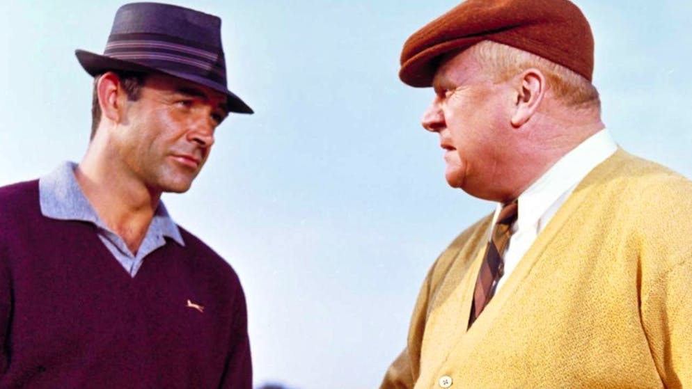 So alt ist der beste Bond-Film schon. Platz 1: Der Schurke Goldfinger (Gert Fröbe, rechts) hat fast sämtliche Goldvorräte der Erde aufgekauft. Nun will er Fort Knox atomisieren und dadurch den Preis für sein eigenes Edelmetall in Schwindel erregende Höhen treiben. Wer sich ihm in den Weg stellt, wird entweder mit einem Goldfarbenüberzug erstickt oder durch die Metallmelone seines Dieners Oddjob geköpft. «Goldfinger» (1965, mit Sean Connery) ist der beste aller Bond-Filme.