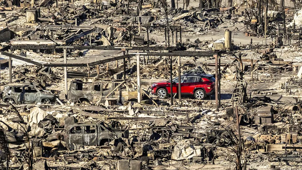 Ein Auto fährt an vom Palisades Fire zerstörten Häusern und Autos im LA-Stadtteil Pacific Palisades vorbei. (12. Januar 2025) 