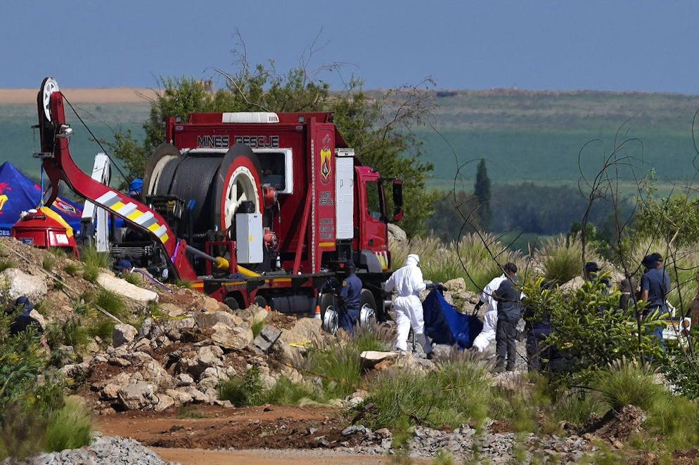 Gerichtsmediziner tragen die Überreste in blauen Leichensäcken während einer Rettungsaktion zur Bergung von Bergleuten unter Tage in einer verlassenen Goldmine in Stilfontein, Südafrika, Dienstag, 14. Januar 2025. (AP Photo/Themba Hadebe)