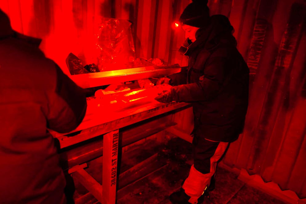 Researchers examine an ice core in the Antarctic under red light.