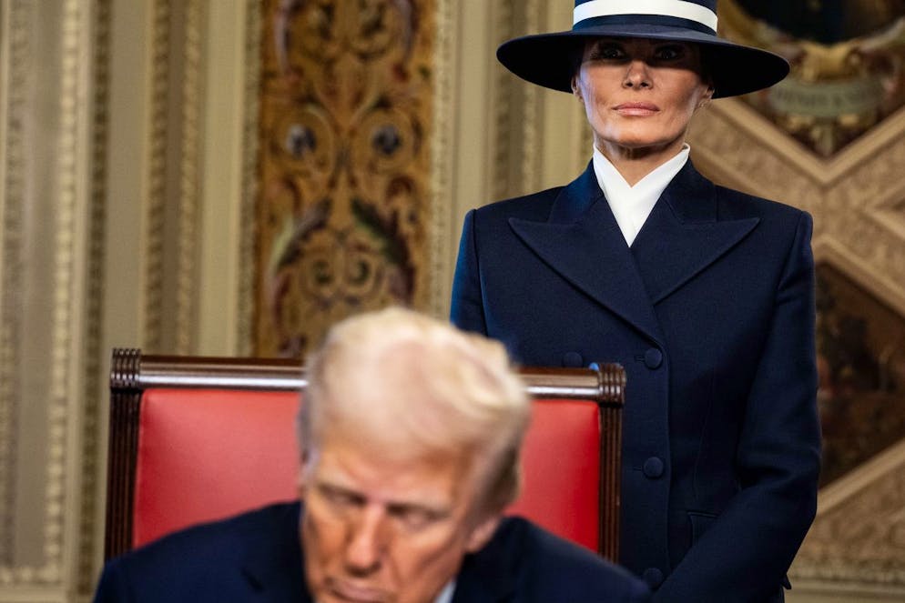 Melania Trump dietro al marito Donald con indosso il cappello che ha fatto tanto parlare i social.
